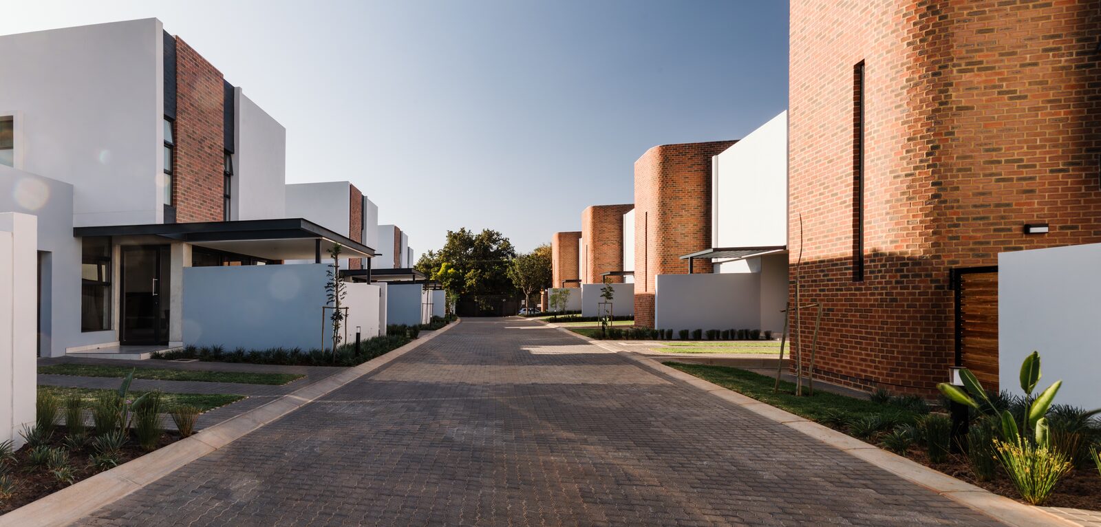 Exterior view of Blanton Villas — contemporary red-brick and white-walled residential units in Lynnwood Glen, Pretoria, designed by Aloe Studio Architects